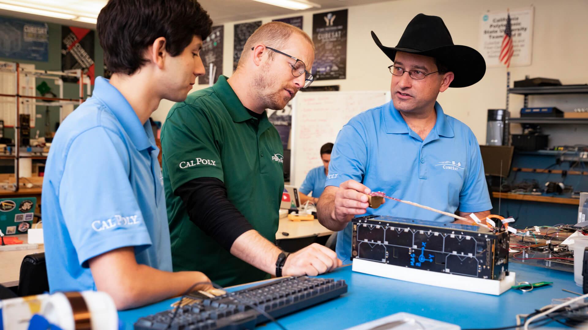 Two students collaborate at a laptop with electronic components connected, testing a hardware interface.